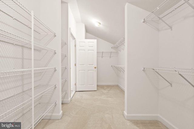 spacious closet featuring lofted ceiling and light colored carpet