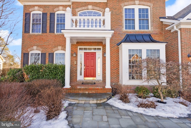 snow covered property entrance featuring a balcony