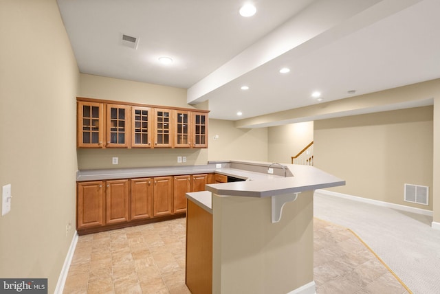 kitchen featuring sink, light colored carpet, kitchen peninsula, and a kitchen bar