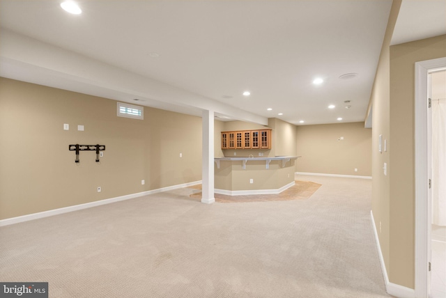 basement with bar and light carpet