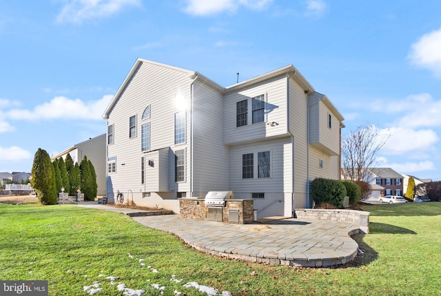 rear view of property featuring an outdoor kitchen, a patio area, and a lawn