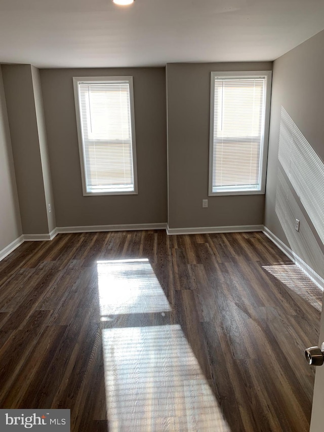 spare room with a healthy amount of sunlight and dark hardwood / wood-style flooring