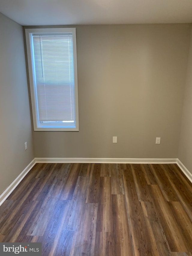 unfurnished room featuring plenty of natural light and dark wood-type flooring