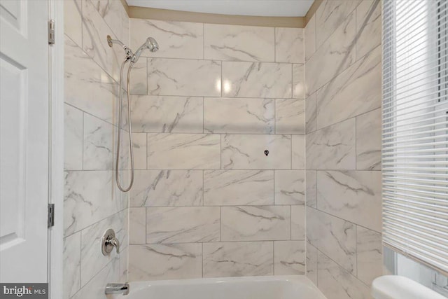 bathroom featuring tiled shower / bath combo and toilet