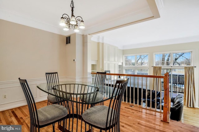 dining room with light hardwood / wood-style floors, ornamental molding, and an inviting chandelier