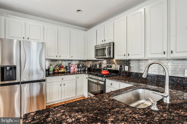 kitchen featuring white cabinetry, sink, appliances with stainless steel finishes, and dark stone counters