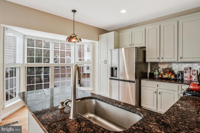 kitchen with white cabinetry, sink, stainless steel refrigerator with ice dispenser, decorative light fixtures, and decorative backsplash