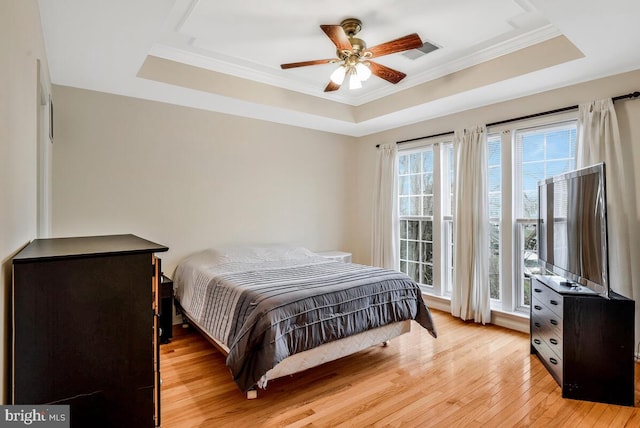 bedroom with light hardwood / wood-style floors, a raised ceiling, and ceiling fan