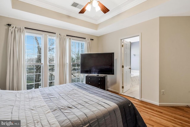 bedroom featuring wood-type flooring, a tray ceiling, ceiling fan, and ensuite bathroom