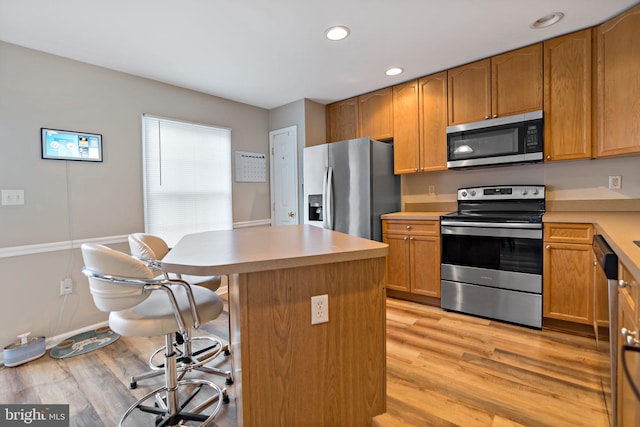 kitchen featuring a kitchen bar, appliances with stainless steel finishes, a center island, and light wood-type flooring