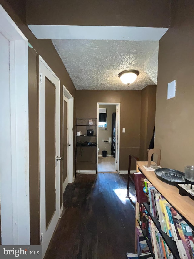 corridor featuring a textured ceiling and dark wood-type flooring