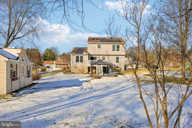 snow covered back of property with solar panels