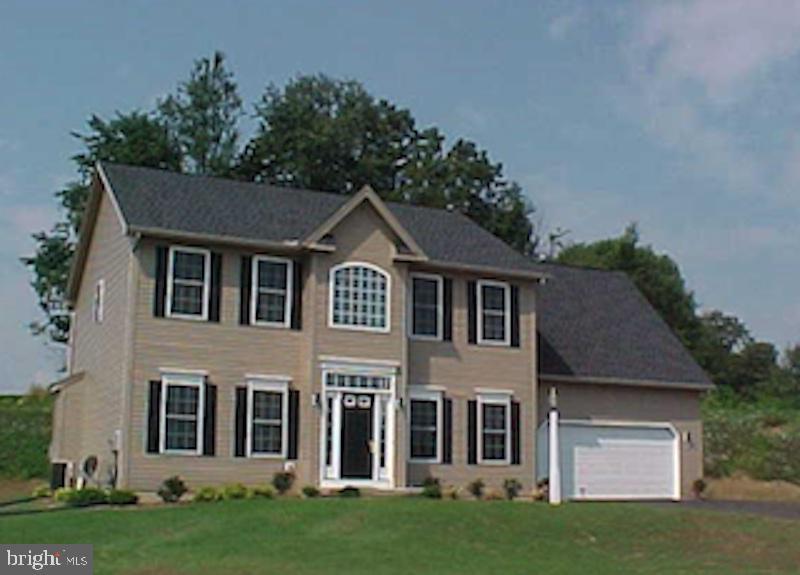 colonial house featuring a garage and a front lawn