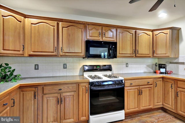 kitchen with ceiling fan, tasteful backsplash, light wood-type flooring, and gas range gas stove