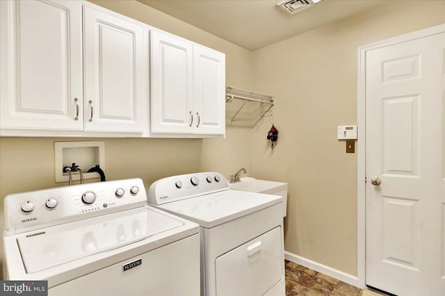 clothes washing area featuring cabinets and independent washer and dryer