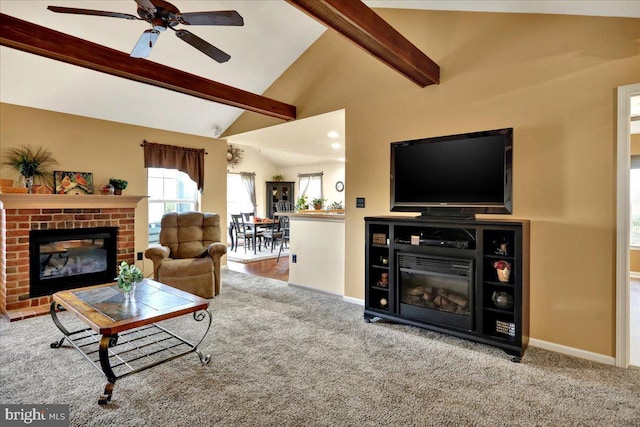 living room with vaulted ceiling with beams, ceiling fan, light carpet, and a brick fireplace