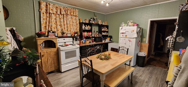 kitchen featuring light wood-type flooring, white appliances, and brick wall