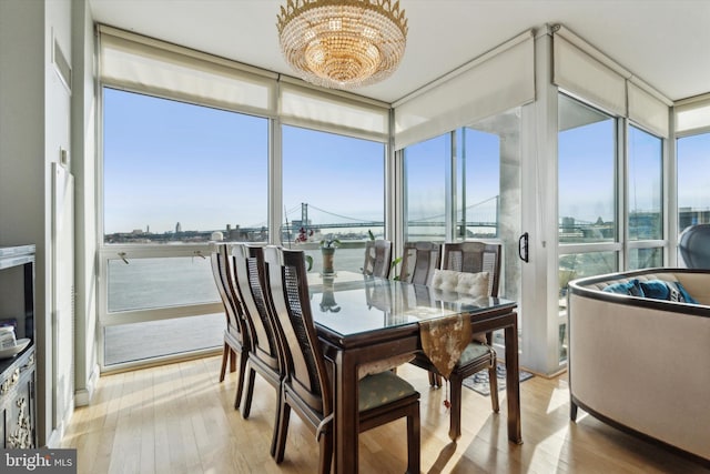 sunroom with a wealth of natural light, a water view, and a chandelier