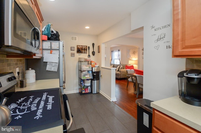 kitchen featuring decorative backsplash, refrigerator, and range