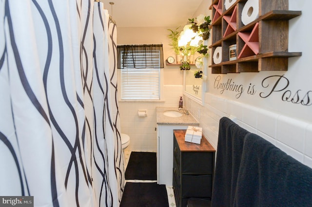 bathroom with vanity, toilet, and tile walls