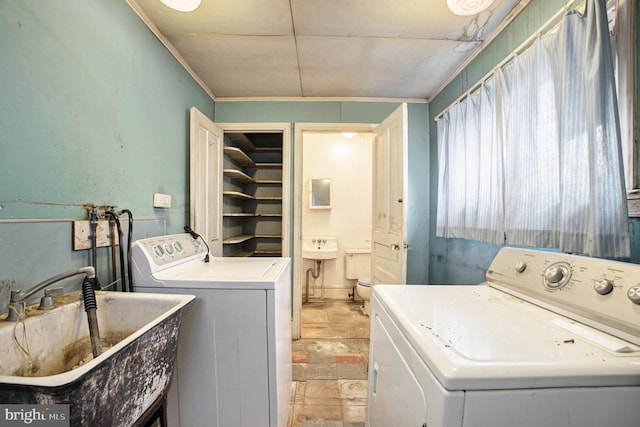 laundry area featuring sink, ornamental molding, and washer and dryer