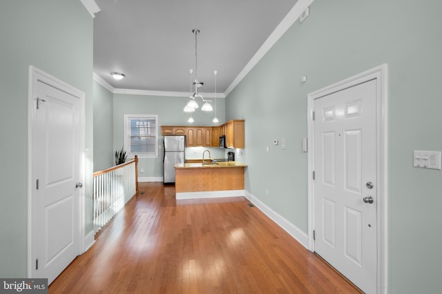 kitchen featuring kitchen peninsula, stainless steel fridge, ornamental molding, decorative light fixtures, and a chandelier