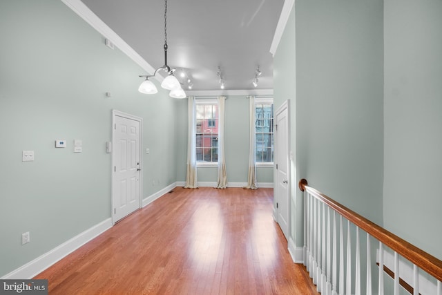 interior space with light wood-type flooring, crown molding, and an inviting chandelier