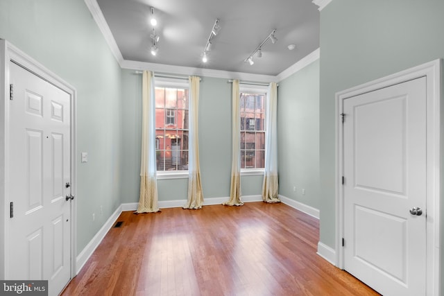 interior space with light hardwood / wood-style floors, ornamental molding, and rail lighting