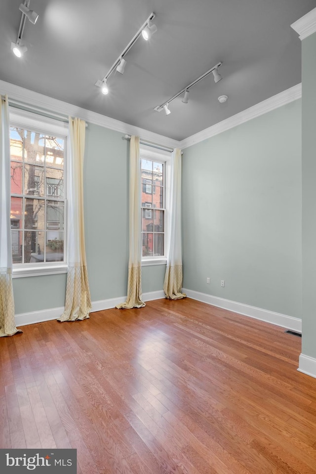 unfurnished room with hardwood / wood-style floors, rail lighting, and ornamental molding