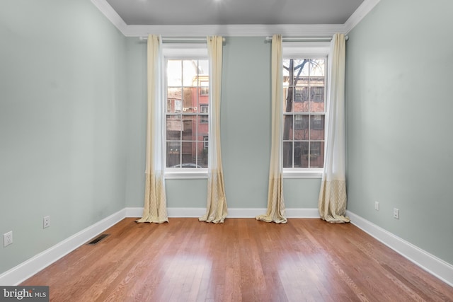 empty room featuring crown molding and light wood-type flooring