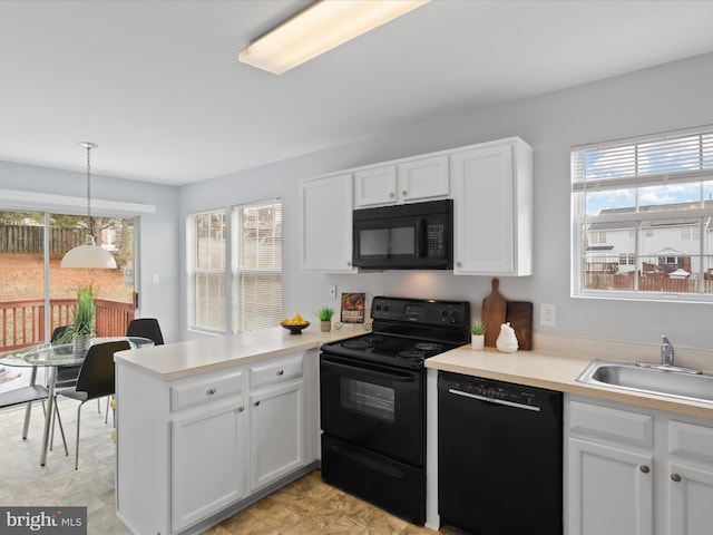 kitchen featuring white cabinetry, sink, decorative light fixtures, and black appliances