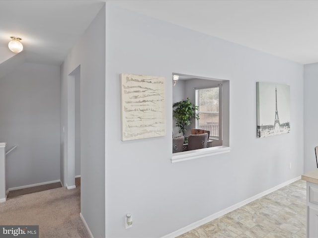 hallway featuring lofted ceiling and light carpet