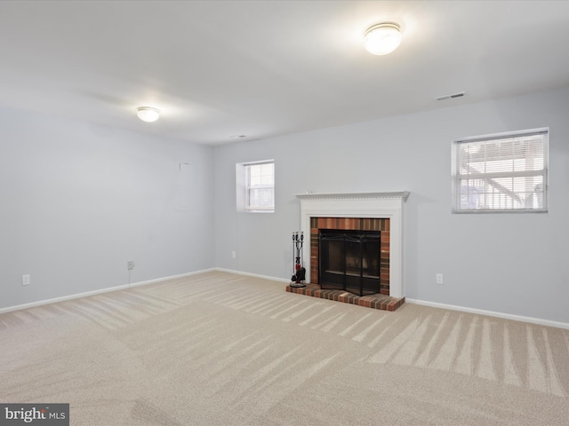 unfurnished living room featuring a brick fireplace and carpet