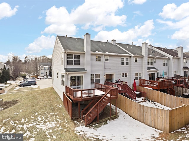 snow covered rear of property with a deck