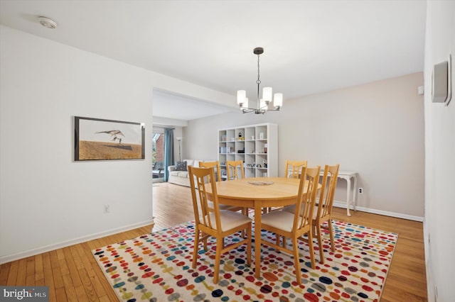 dining space with wood-type flooring and a notable chandelier