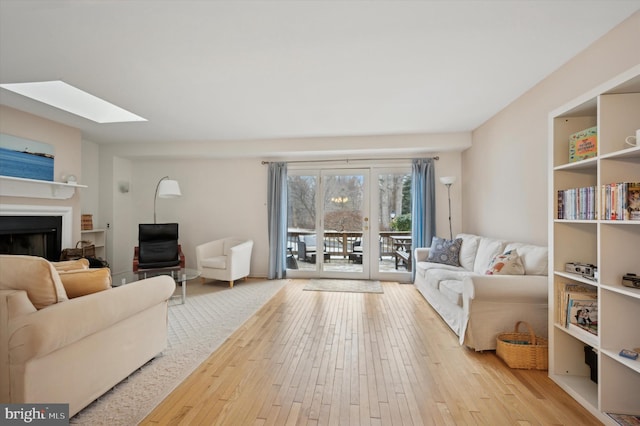 living room featuring a skylight and light hardwood / wood-style flooring