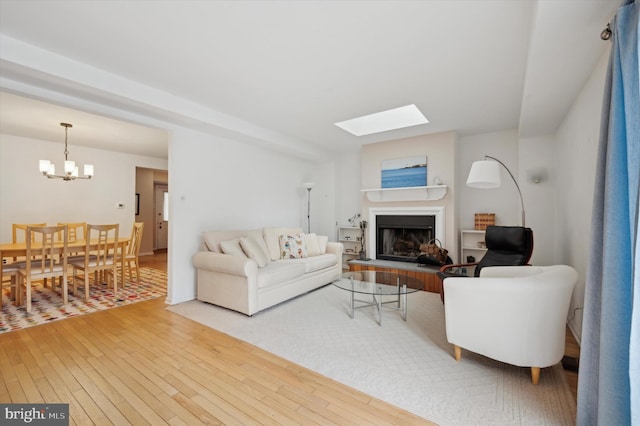 living room featuring a skylight, a notable chandelier, and hardwood / wood-style flooring