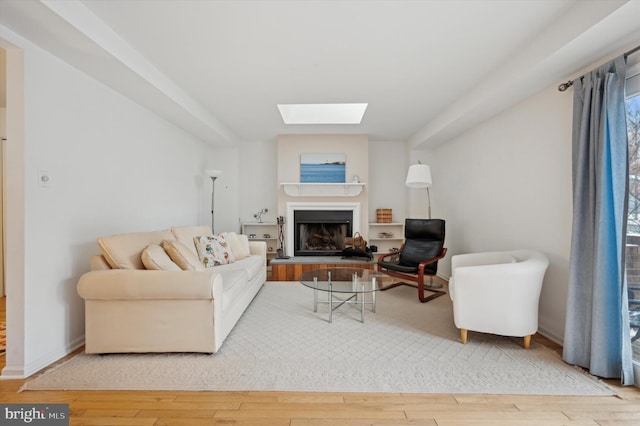 living room featuring a healthy amount of sunlight, a skylight, and wood-type flooring