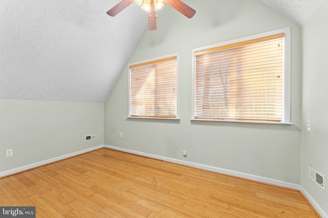 bonus room featuring vaulted ceiling, a textured ceiling, and light wood-type flooring