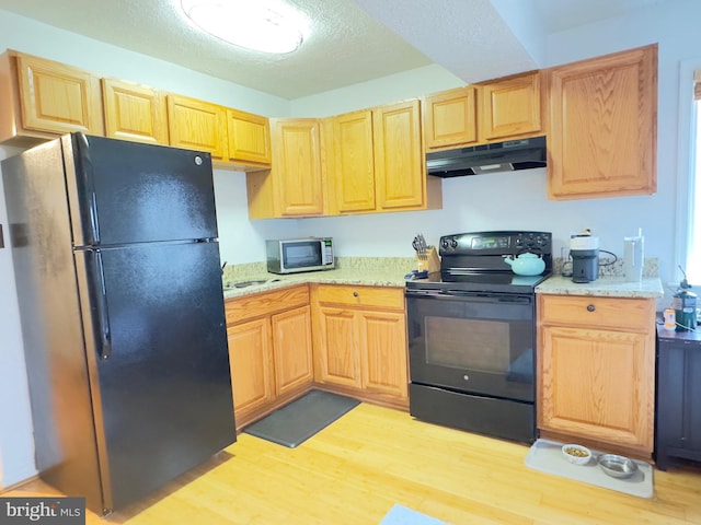 kitchen featuring light stone counters, black appliances, a textured ceiling, and light wood-type flooring