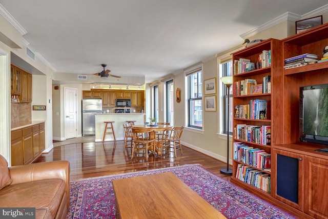 interior space with ceiling fan, ornamental molding, and dark wood-type flooring