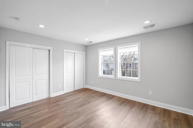 unfurnished bedroom featuring multiple closets and hardwood / wood-style flooring