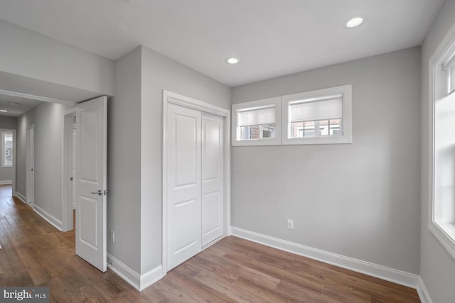 unfurnished bedroom featuring a closet, light wood-type flooring, and multiple windows