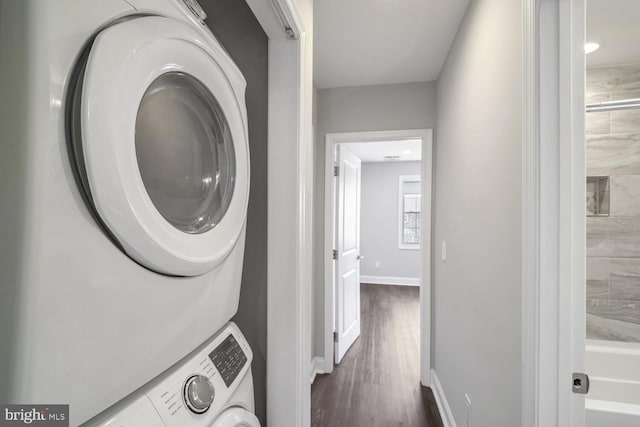 laundry room with stacked washer and dryer and dark wood-type flooring