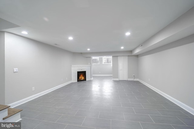 basement with a fireplace and dark tile patterned floors