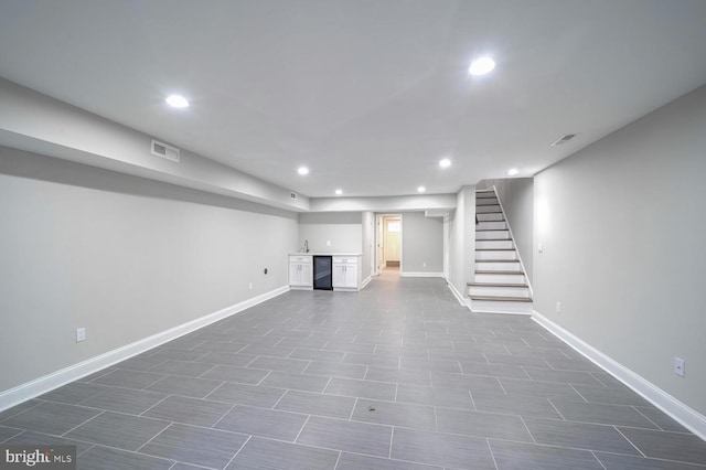 basement with bar, wine cooler, and dark tile patterned flooring