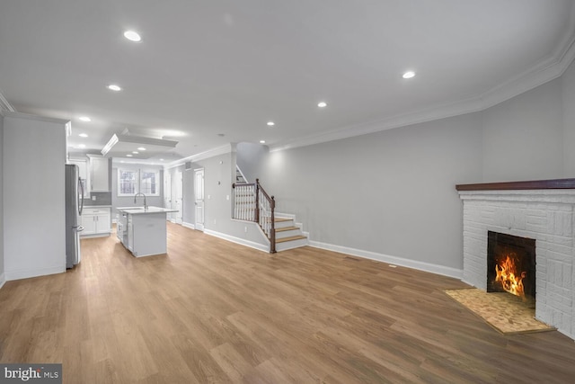 unfurnished living room featuring light hardwood / wood-style flooring, a stone fireplace, and ornamental molding