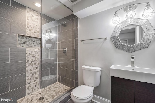 bathroom with vanity, toilet, and tiled shower