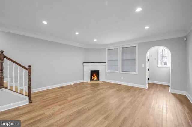 unfurnished living room featuring a fireplace, light wood-type flooring, and crown molding