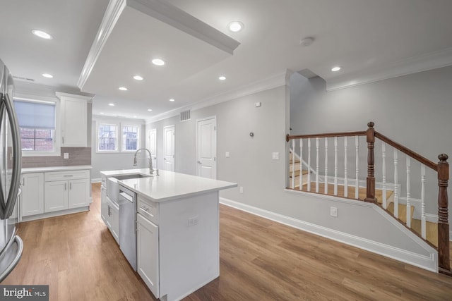 kitchen with white cabinetry, crown molding, an island with sink, decorative backsplash, and appliances with stainless steel finishes